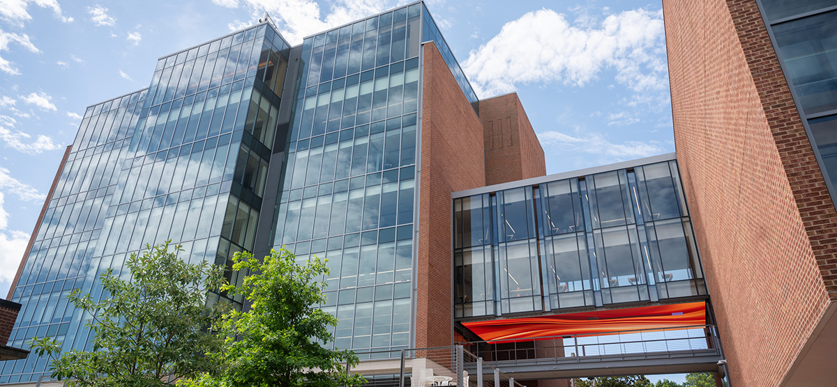 exterior of a glass-fronted building with blue sky and clouds above it