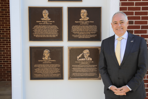 Georgia Tech President Angel Cabrera standing next to brass plaques
